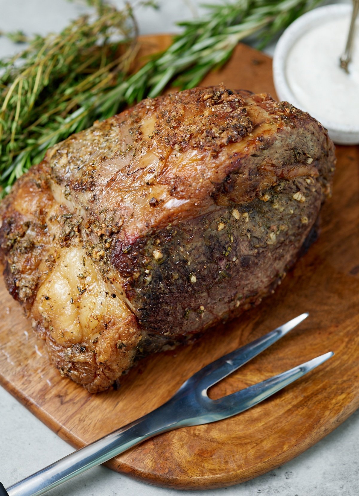 The cooked boneless roast beef on a wooden chopping board with a carving fork.