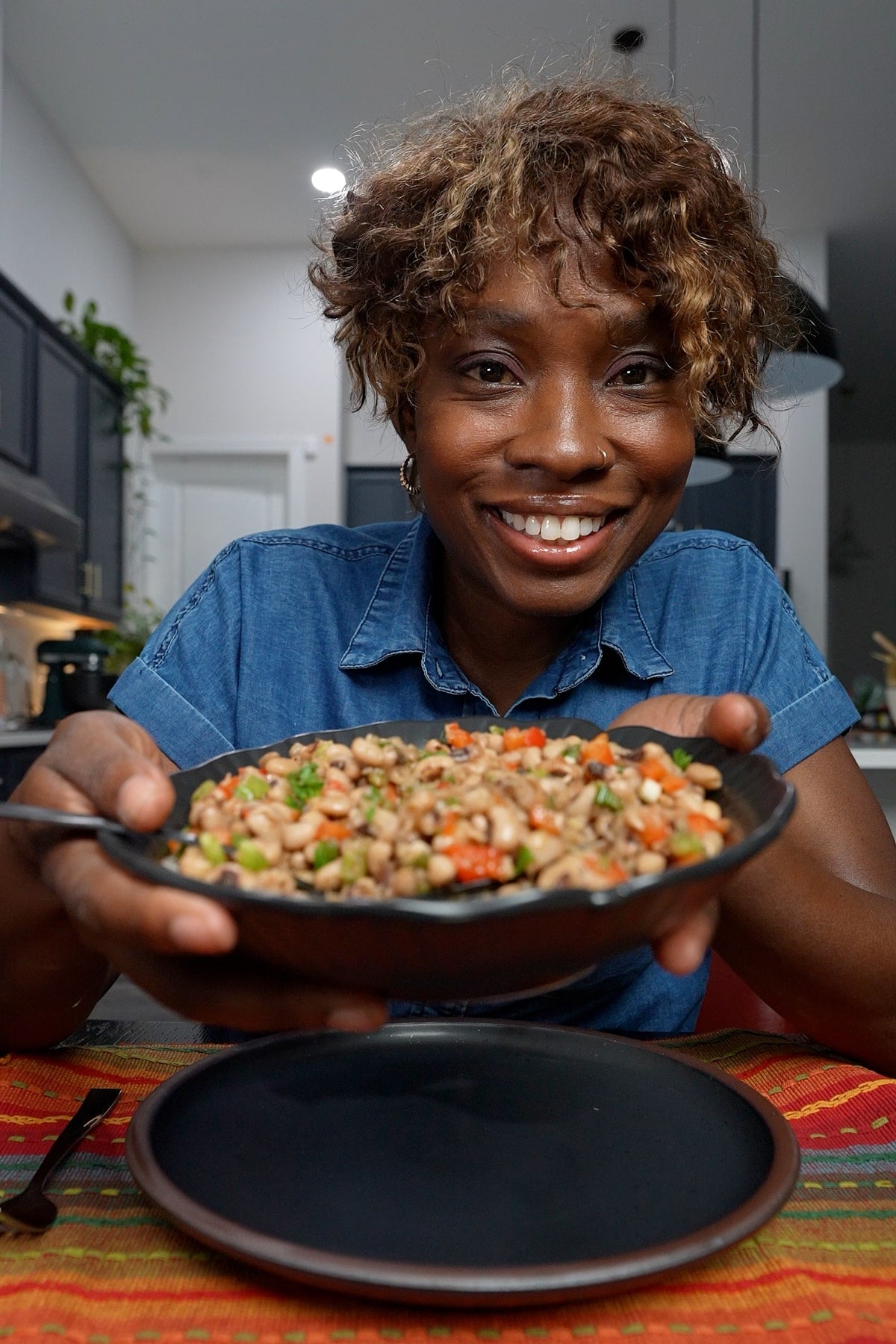 Tanya holding a bowl of black eyed peas, smiling
