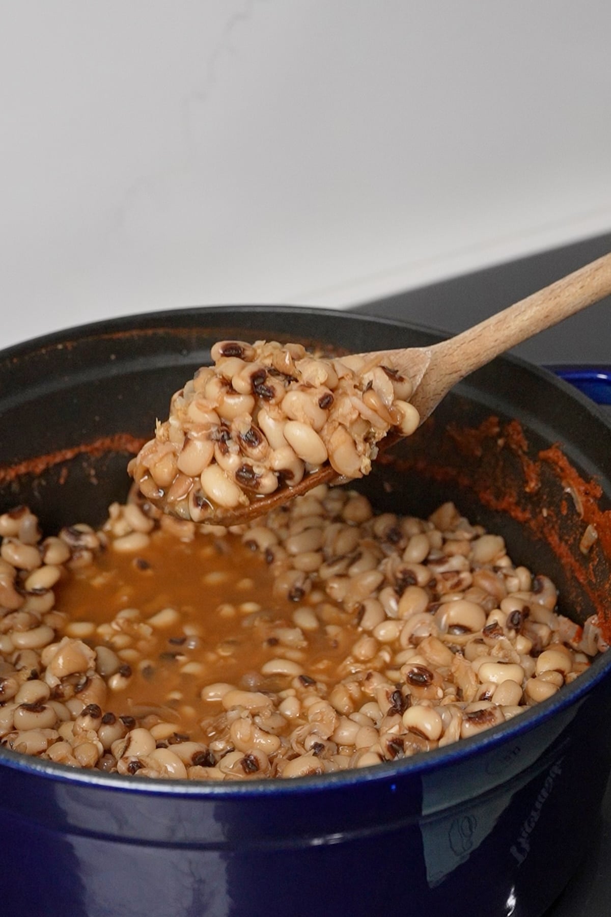Spoon lifting cooked black eyed peas out of the pot.