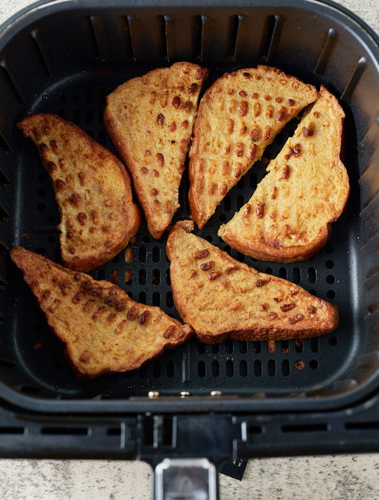Cooked pieces of French toast in the air fryer basket.