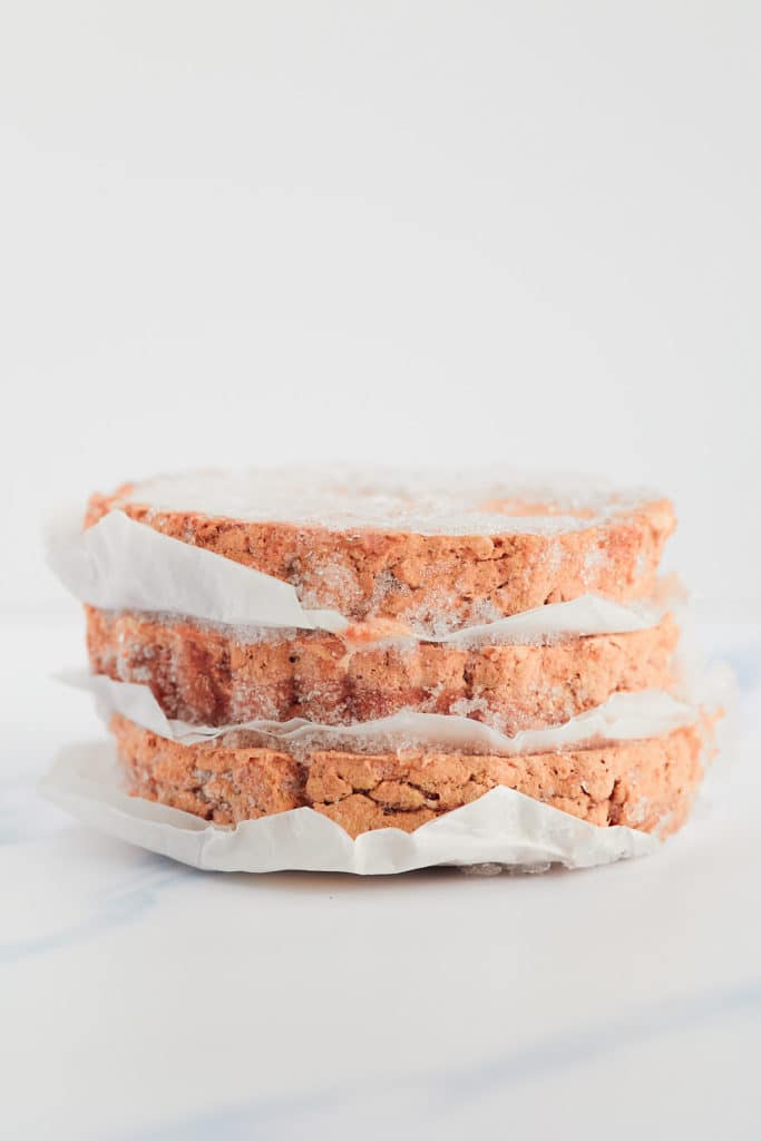 Three frozen hamburgers separated with parchment.