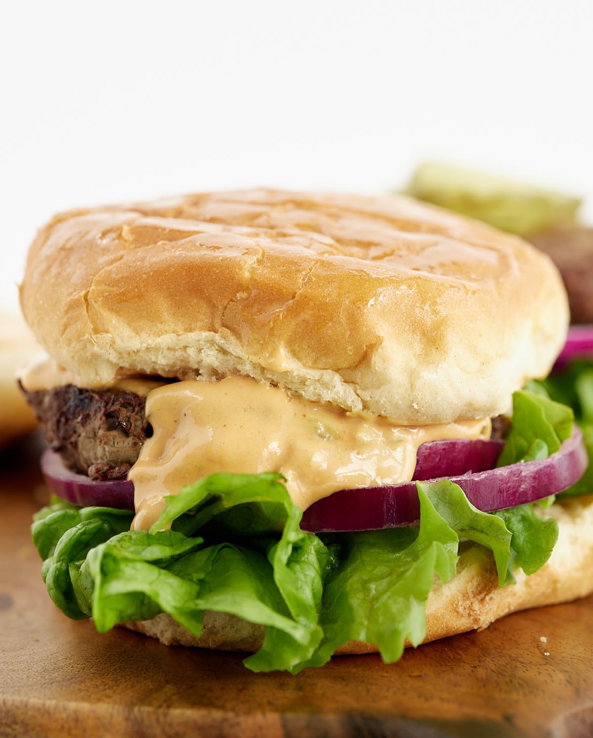 Close up of a hamburger in a bun with toppings.