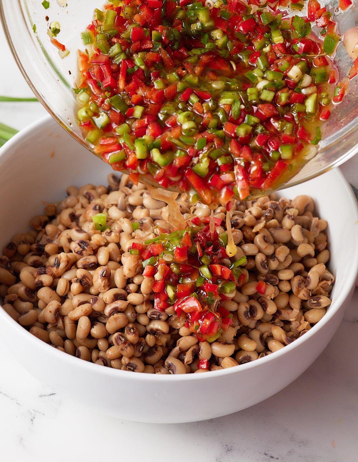 Vinaigrette being poured over the black eyed peas.