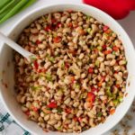 Black eyed pea salad in a white serving bowl with a spoon.