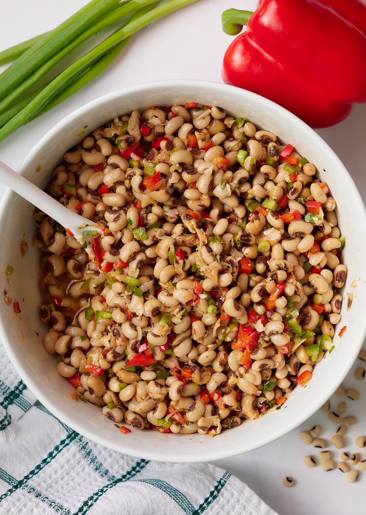 Black eyed pea salad in a white serving bowl with a spoon.