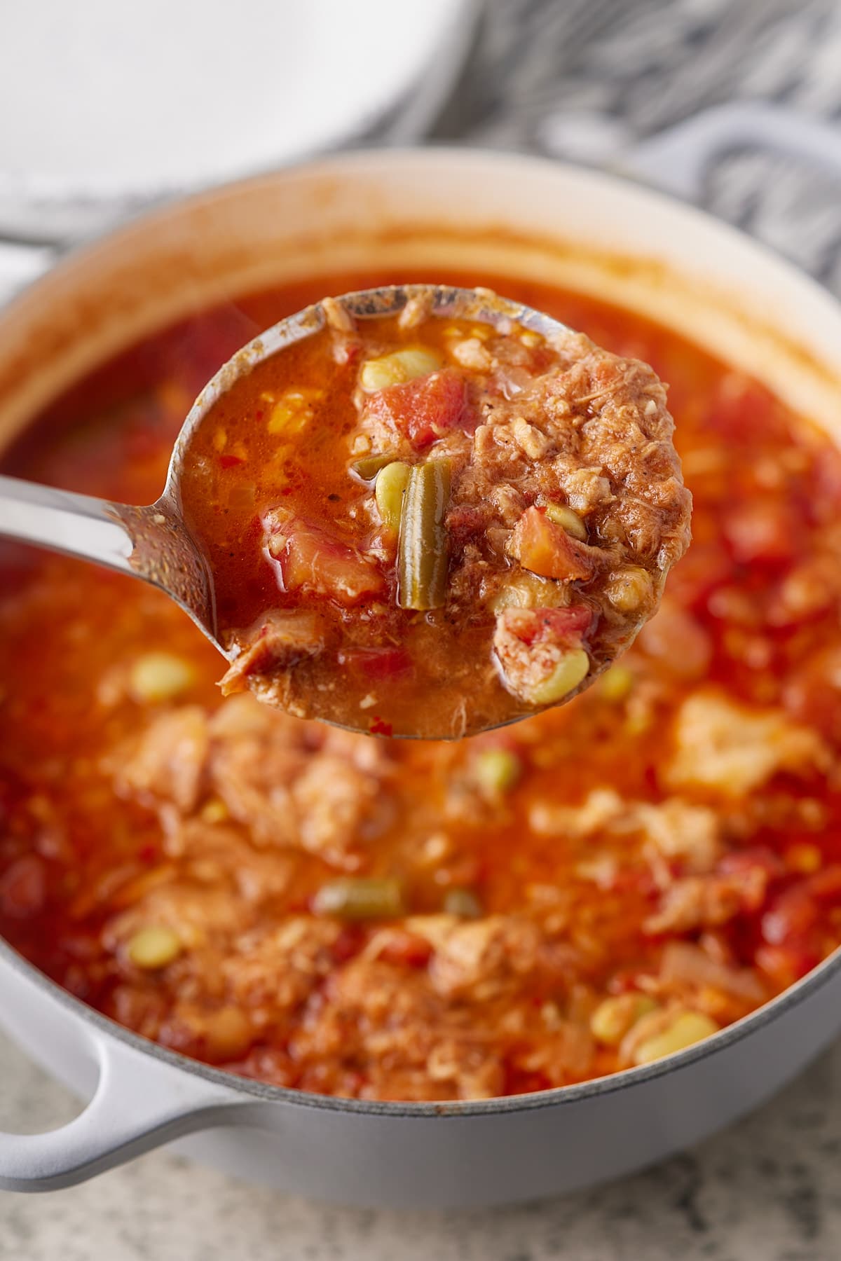 Brunswick stew on a ladle above the pot it was cooked in.