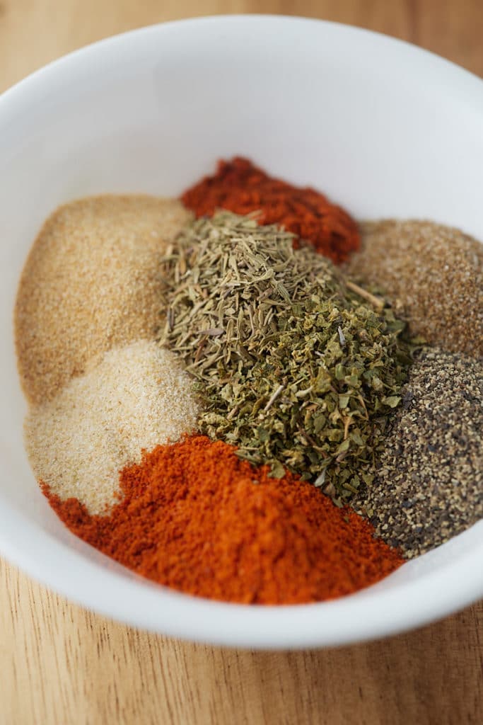 Dried herbs and spices in a white bowl.