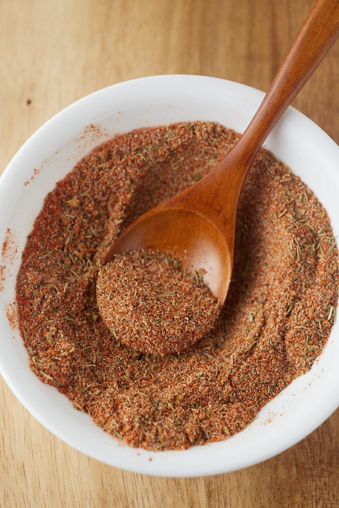 Herbs and spices mixed together with a wooden spoon.