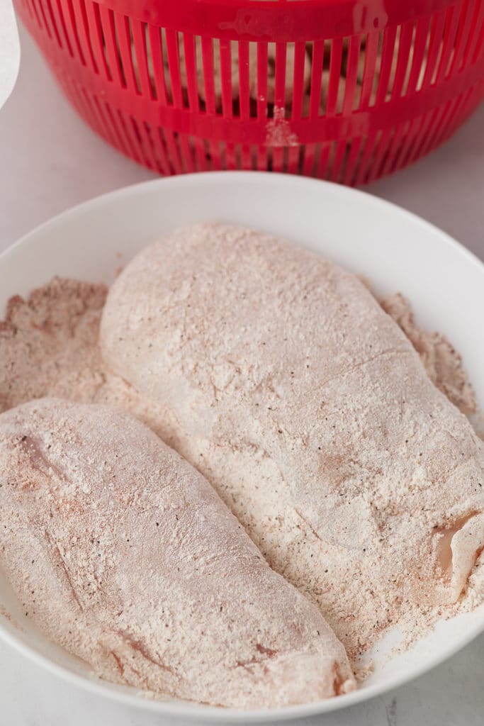 Chicken breasts coated with seasoned flour.
