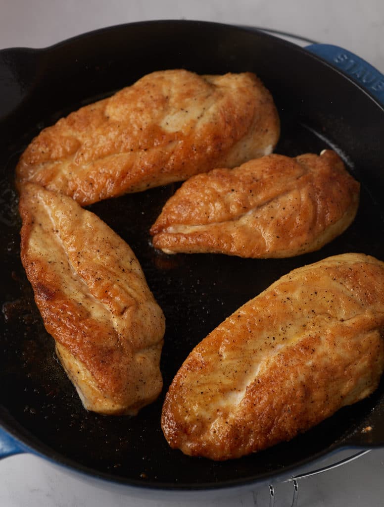 Browned chicken breasts in a skillet.