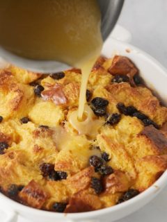 Bourbon sauce being poured over the bread pudding.