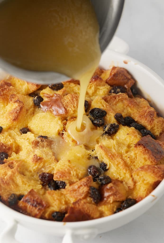 Bourbon sauce being poured over the bread pudding.