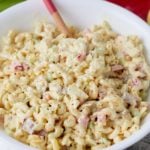 A spoon in a bowl of creamy macaroni salad.