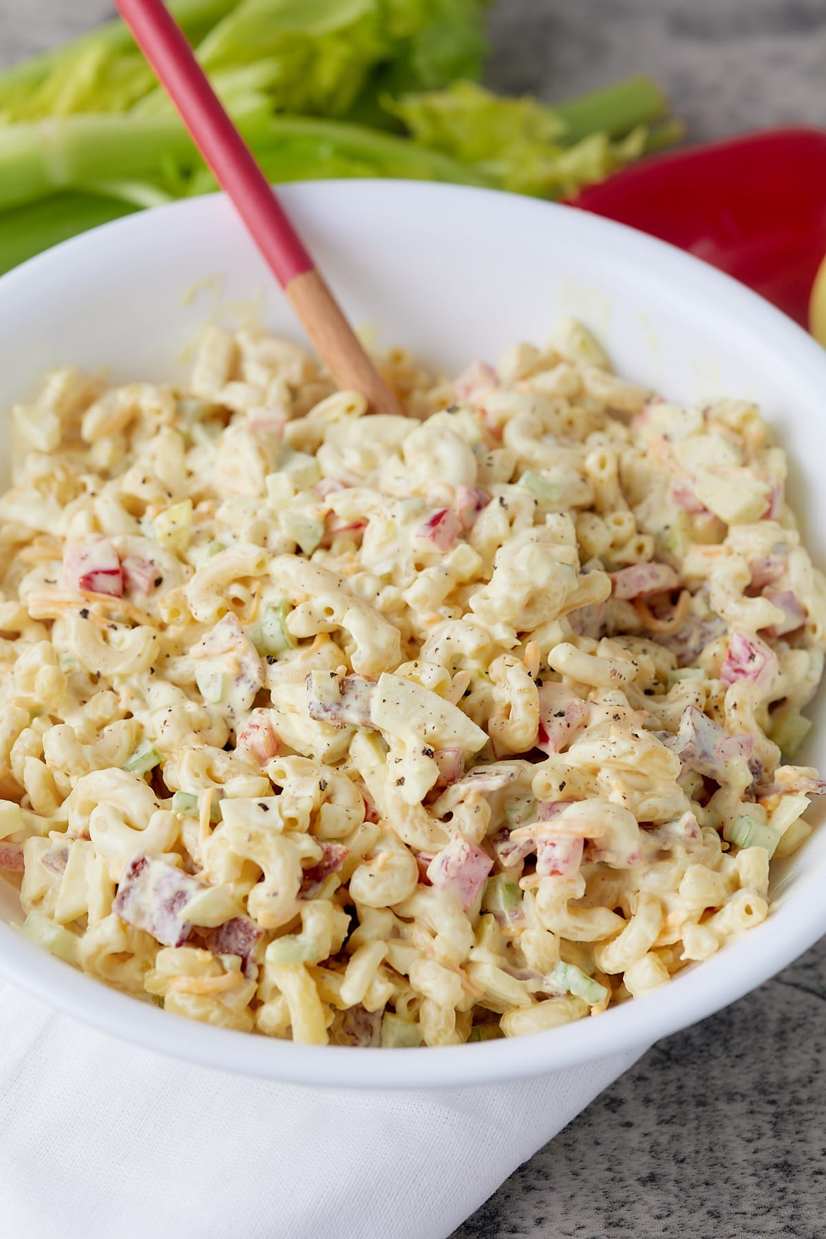 A spoon in a bowl of creamy macaroni salad.