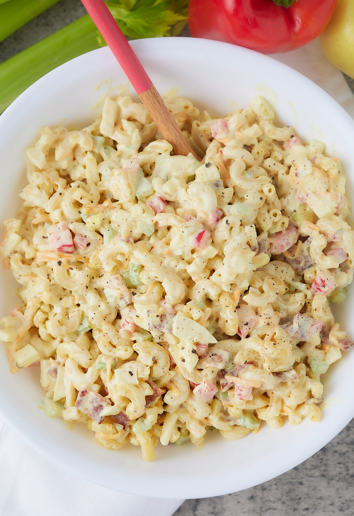 Overhead shot of Southern style macaroni salad in a white bowl with a spoon.
