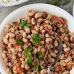 Blackeye peas served in a bowl next to a side dish of rice.