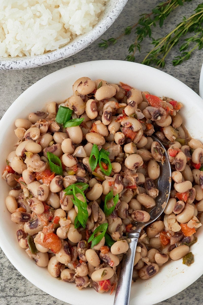 Blackeye peas served in a bowl next to a side dish of rice.