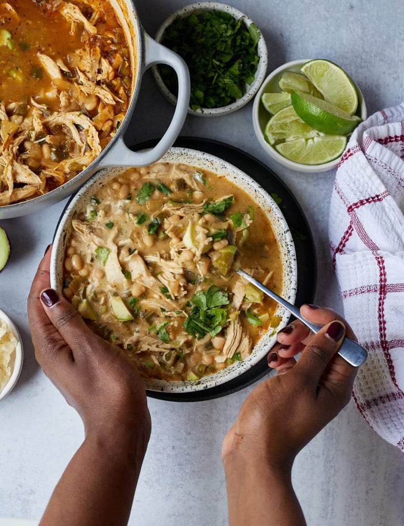 hand holding bowl of chicken chili to eat