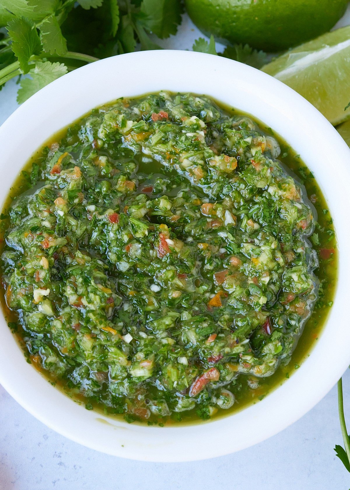 green seasonong in white plate with herbs surrounding it