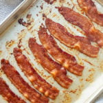 Eight strips of bacon on a baking sheet ready to serve.