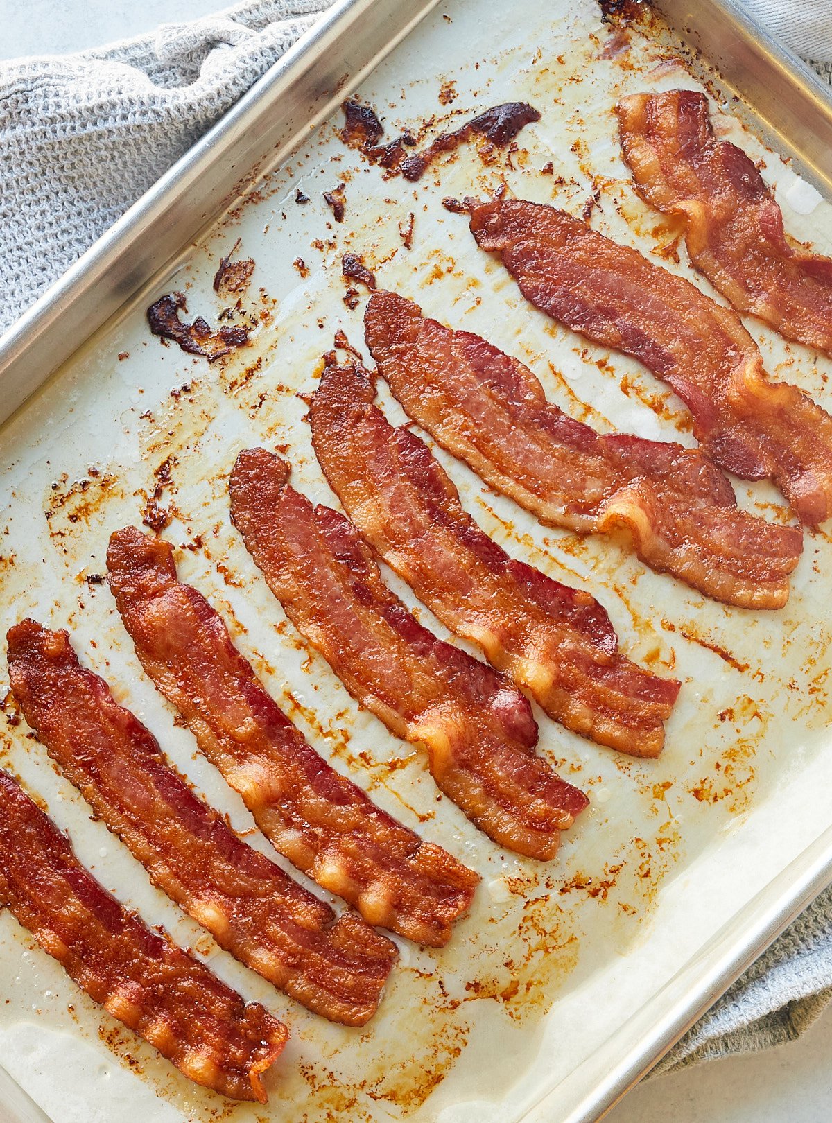Eight strips of bacon on a baking sheet ready to serve.