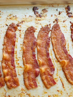 Close up of four strips of oven cooked bacon.
