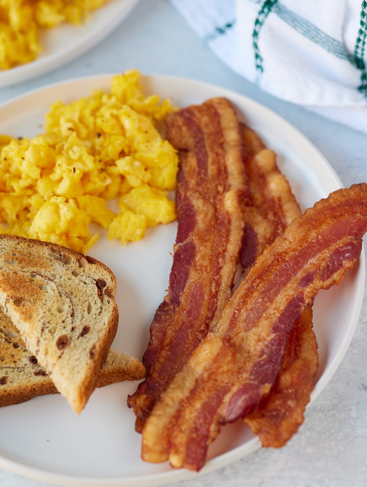 Oven baked bacon served with scrambled eggs and toast.