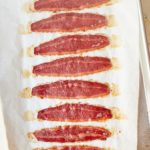 Eight strips of oven baked turkey bacon on a baking sheet.