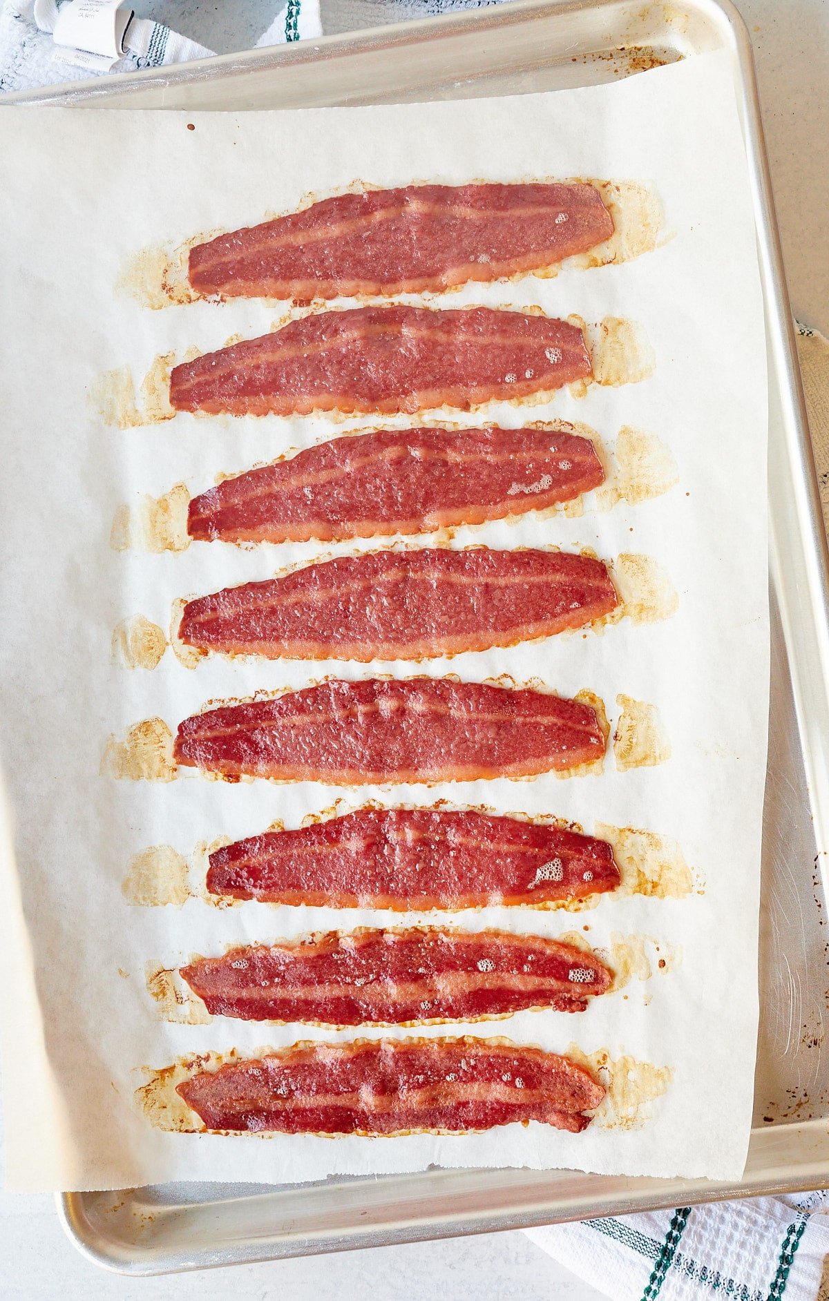 Eight strips of oven baked turkey bacon on a baking sheet.