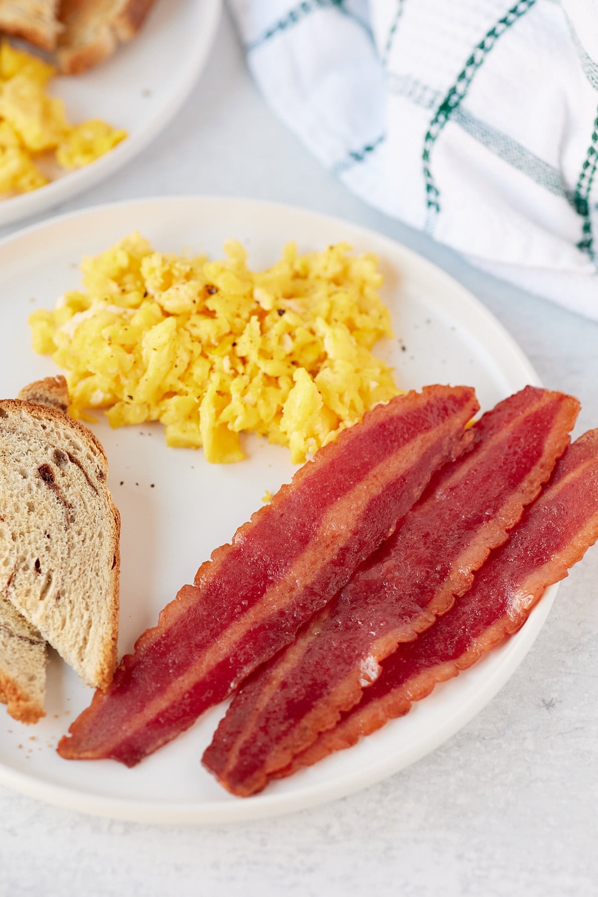 Turkey bacon served on a plate with scrambled eggs and toast.