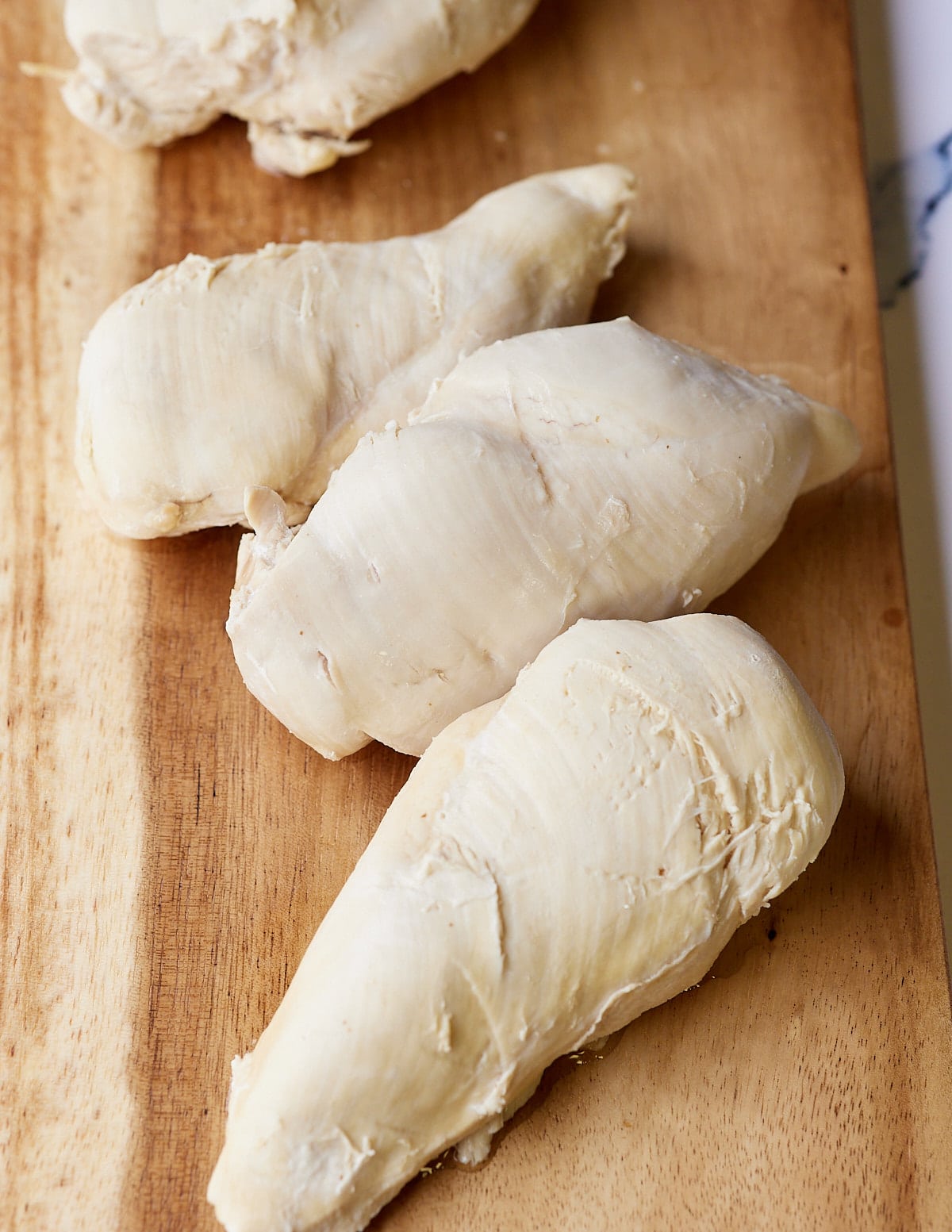 whole boiled chicken breast on wooden board