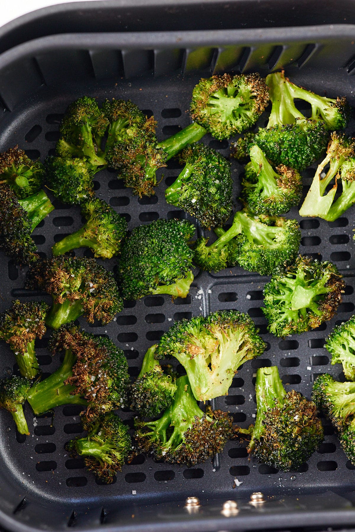 Roasted broccoli in an air fryer basket.
