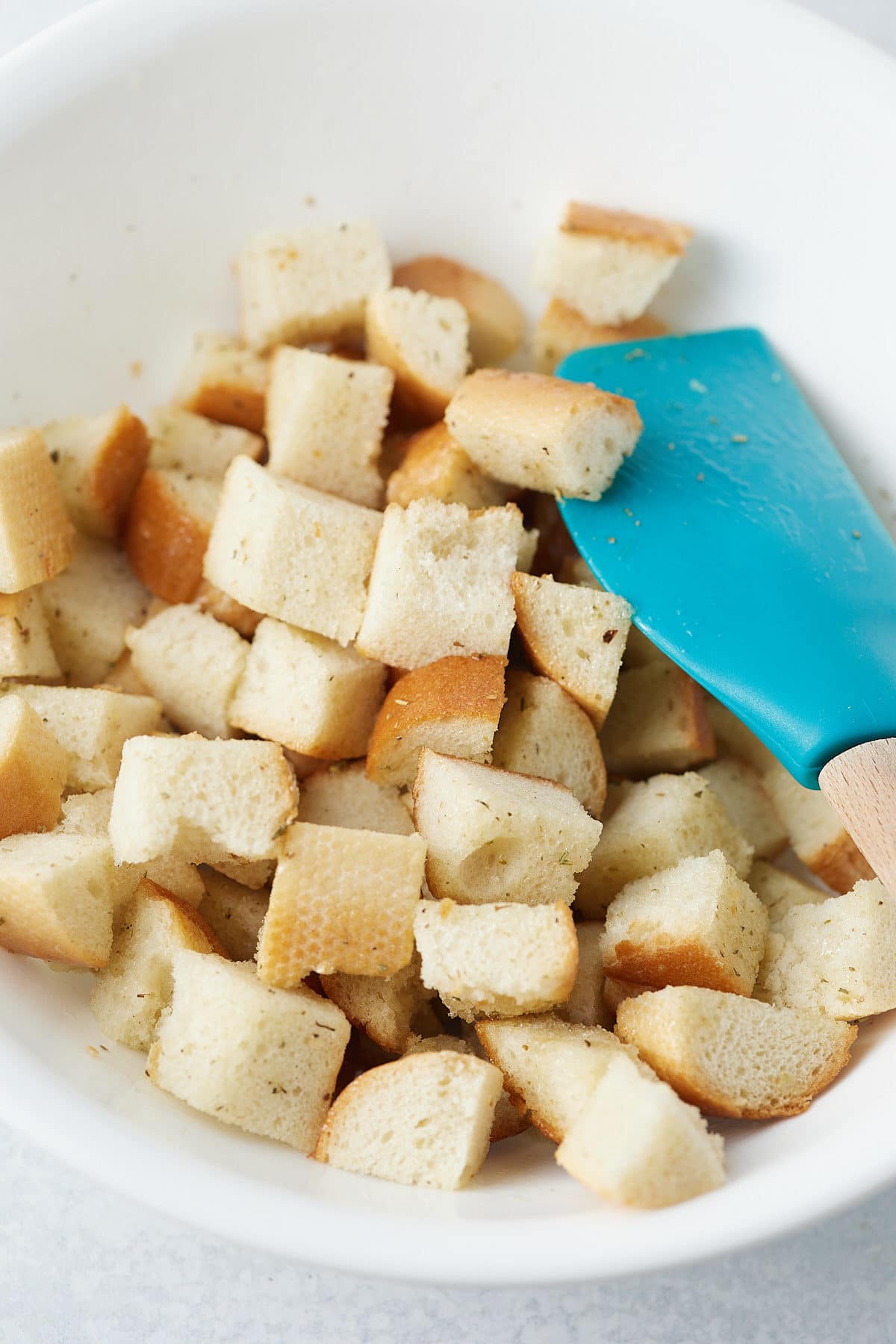 Bread cubes being mixed with oil and seasonings.