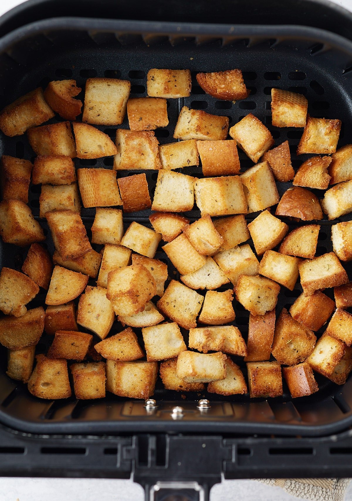 Air fried croutons in an air fryer basket.