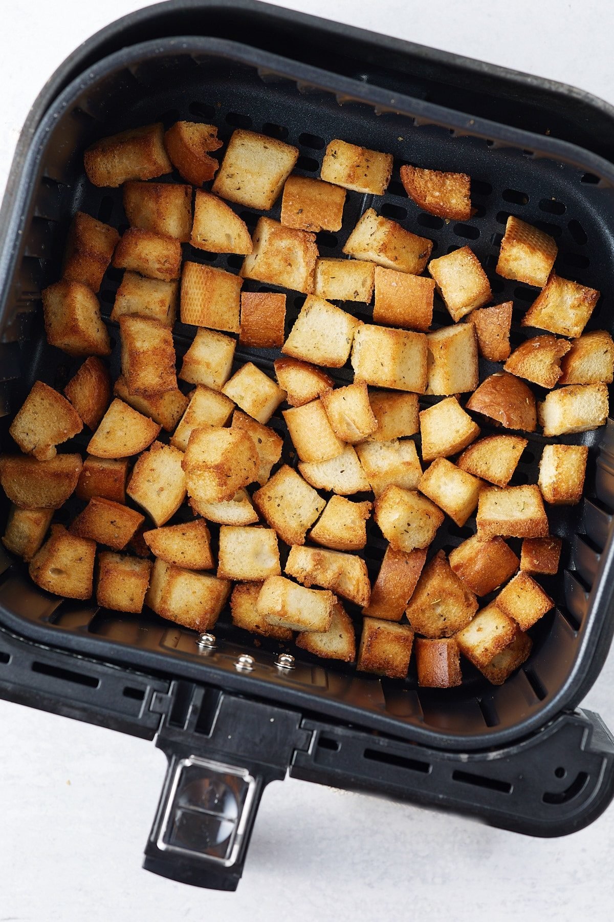 Golden brown croutons in the air fryer basket.