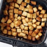 Golden brown croutons in the air fryer basket.