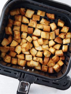Golden brown croutons in the air fryer basket.