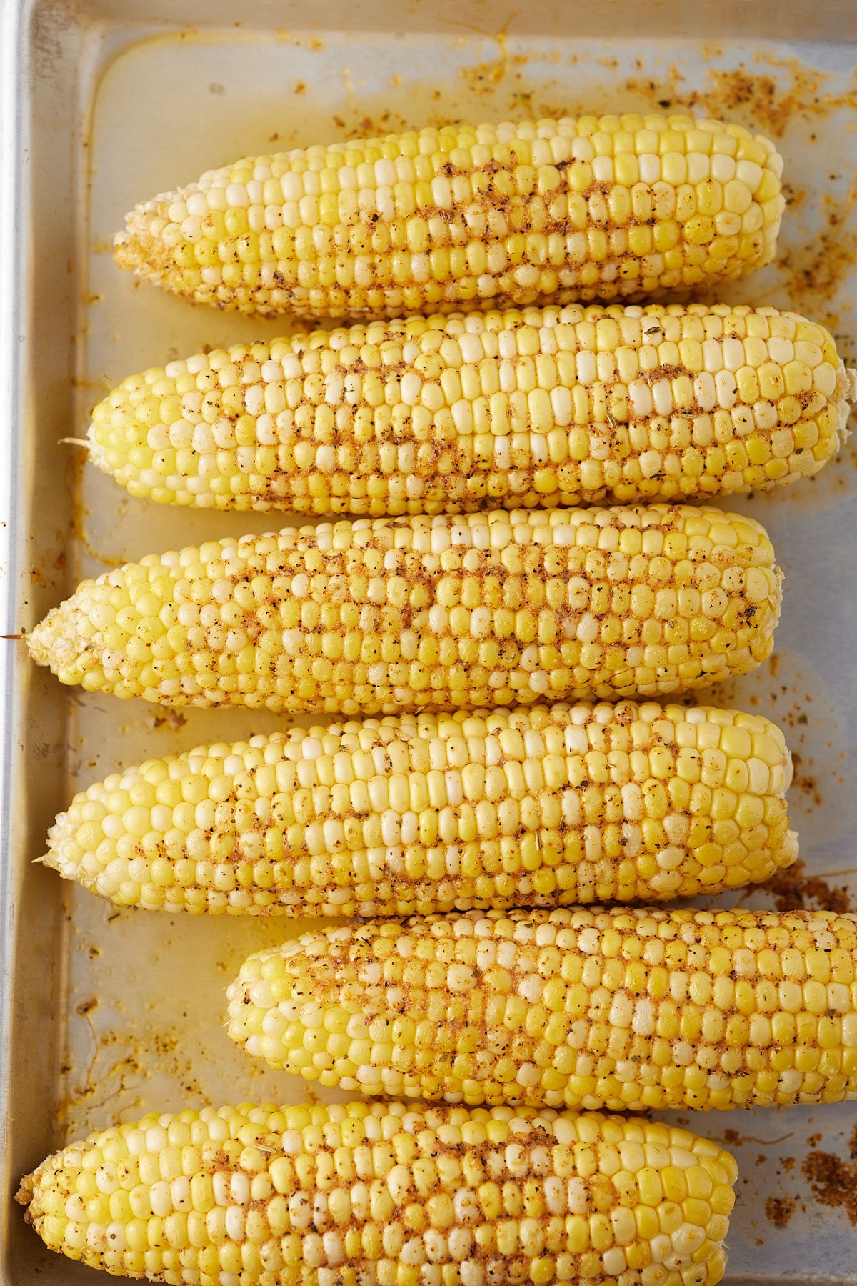 Cooked corn on the cob on a baking sheet.