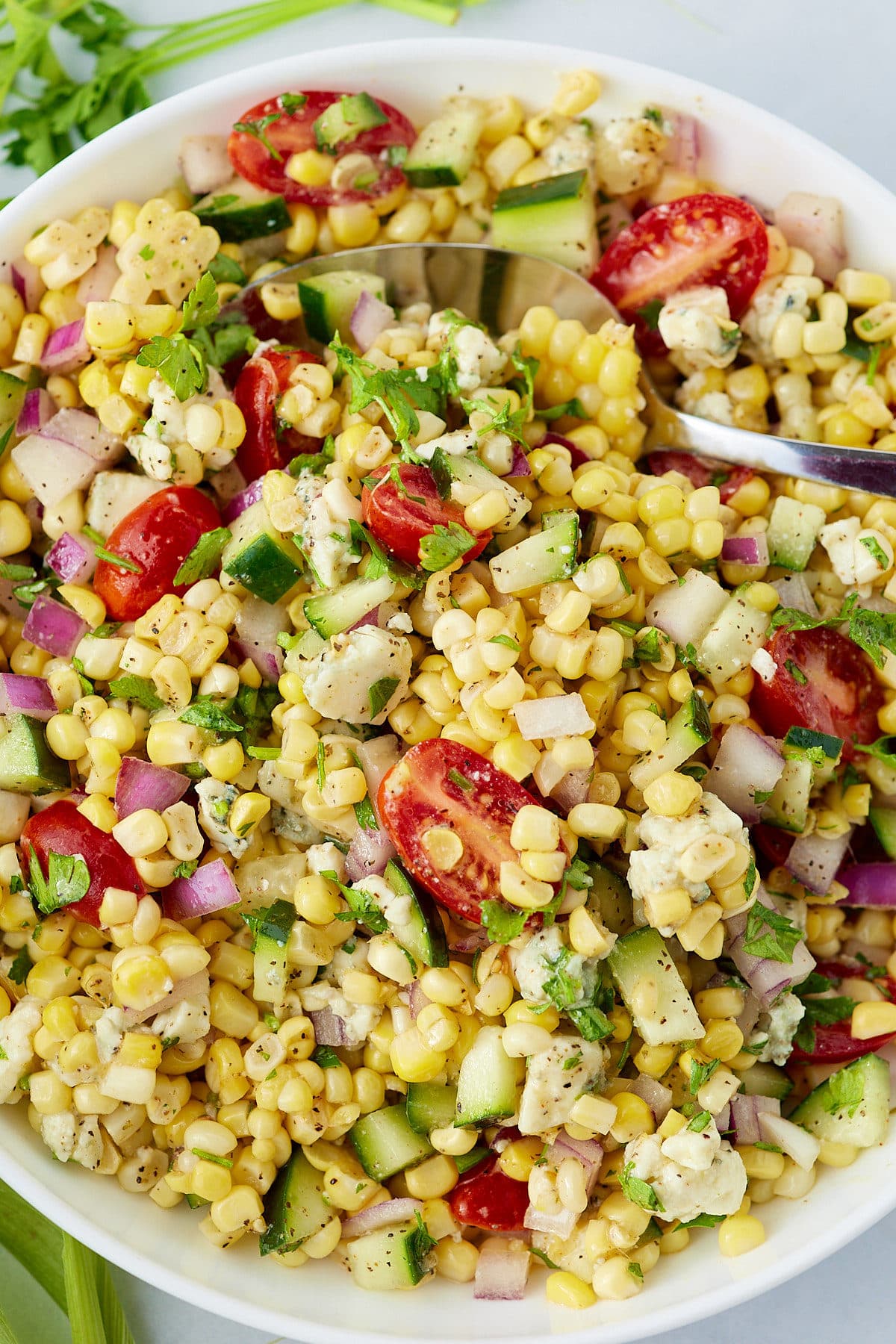 Overhead shot of a corn salad served in a white bowl.