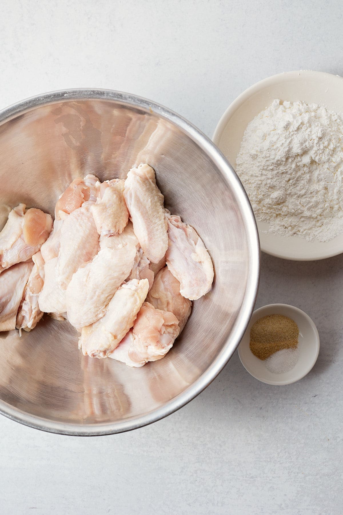 Chicken wings being seasoned.