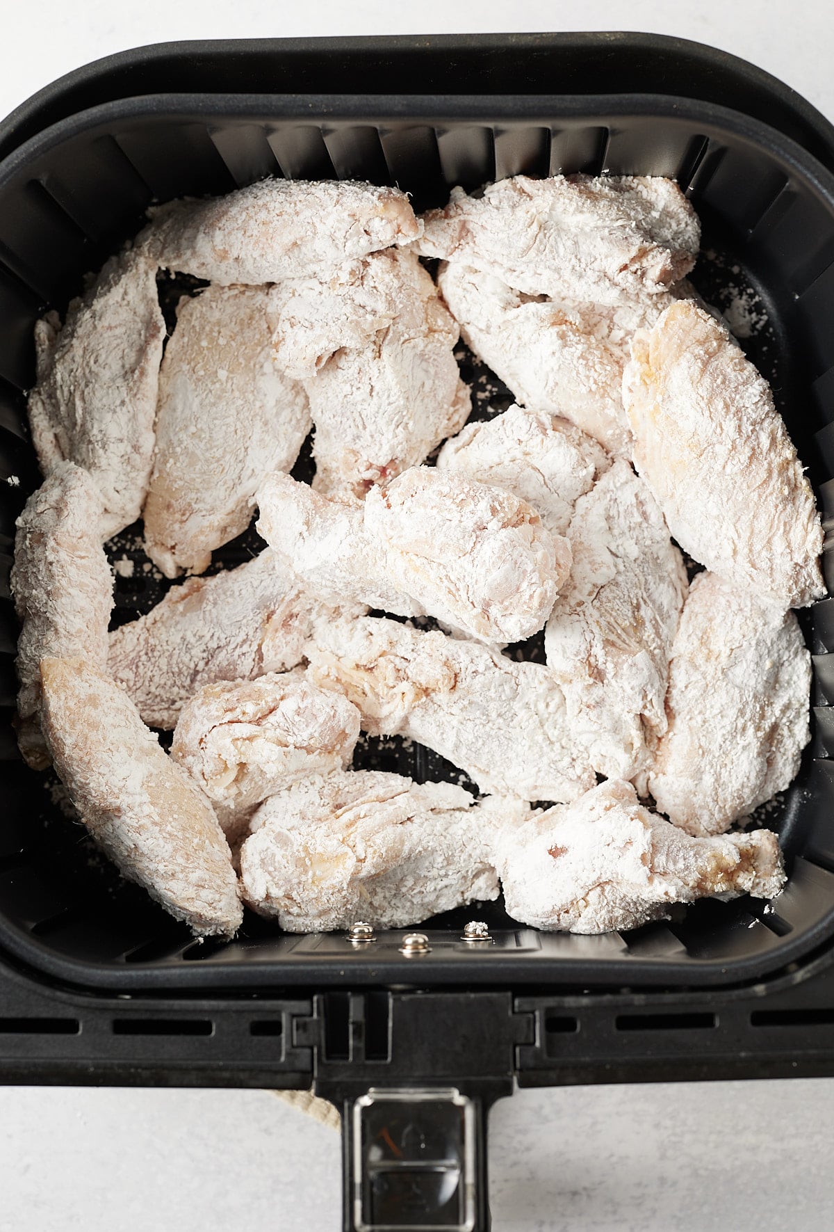 Uncooked wings in the air fryer basket.