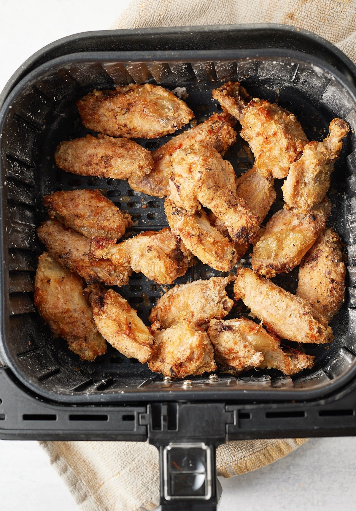 Cooked wings in the air fryer basket.