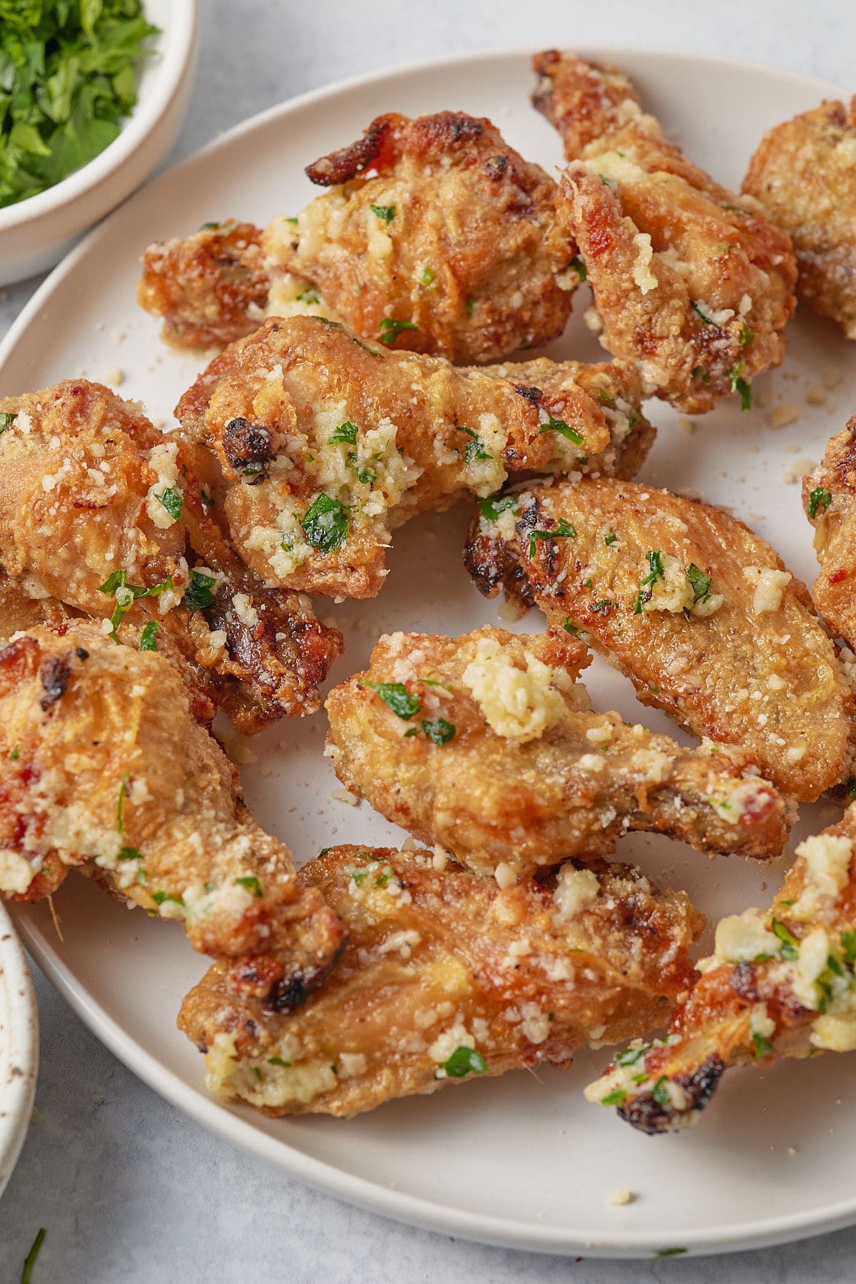 Garlic parm wings served on a white plate.