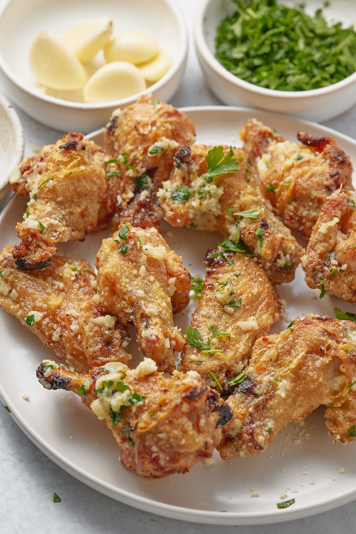 Chicken wings in a garlic parmesan sauce served on a plate.