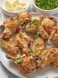 Chicken wings in a garlic parmesan sauce served on a plate.