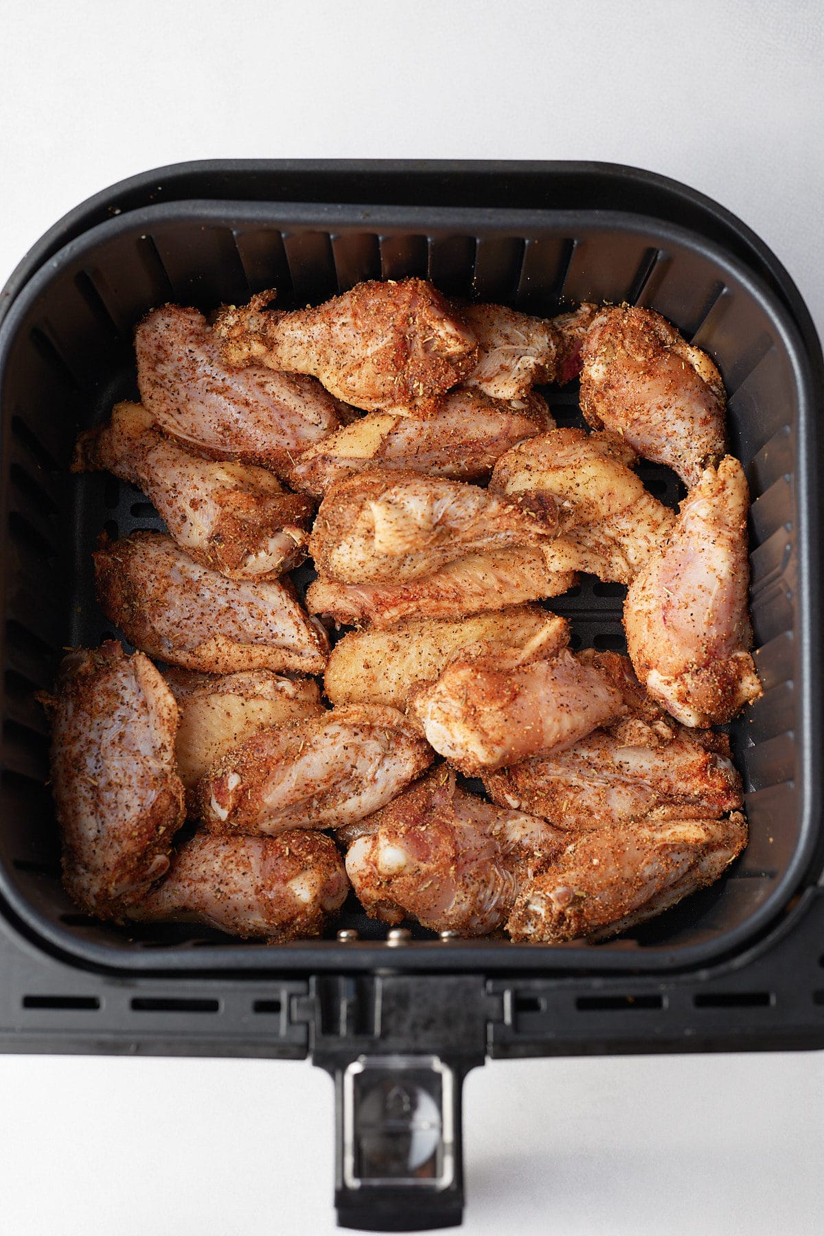 Chicken wings in an air fryer basket.