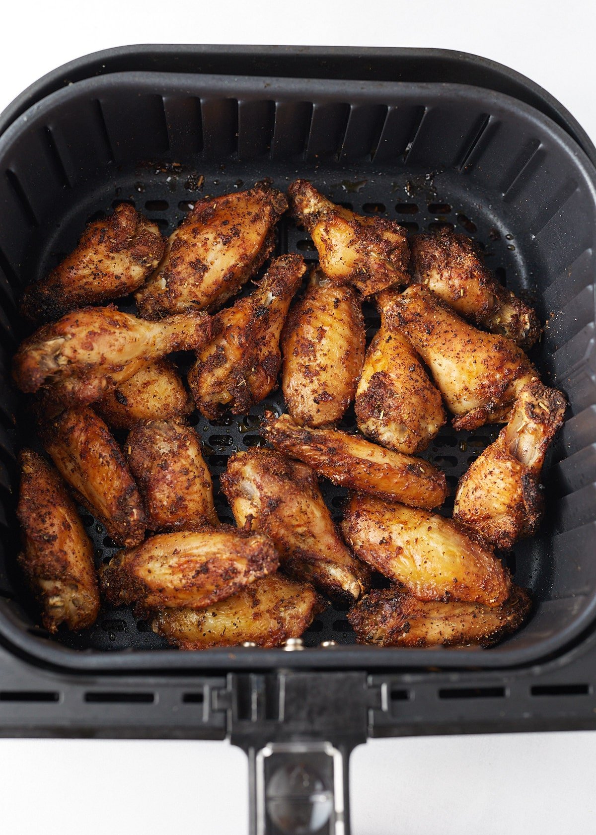 Cooked wings in an air fryer basket.