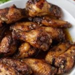 Honey garlic chicken wings served on a white plate.