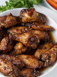 Honey garlic chicken wings served on a white plate.