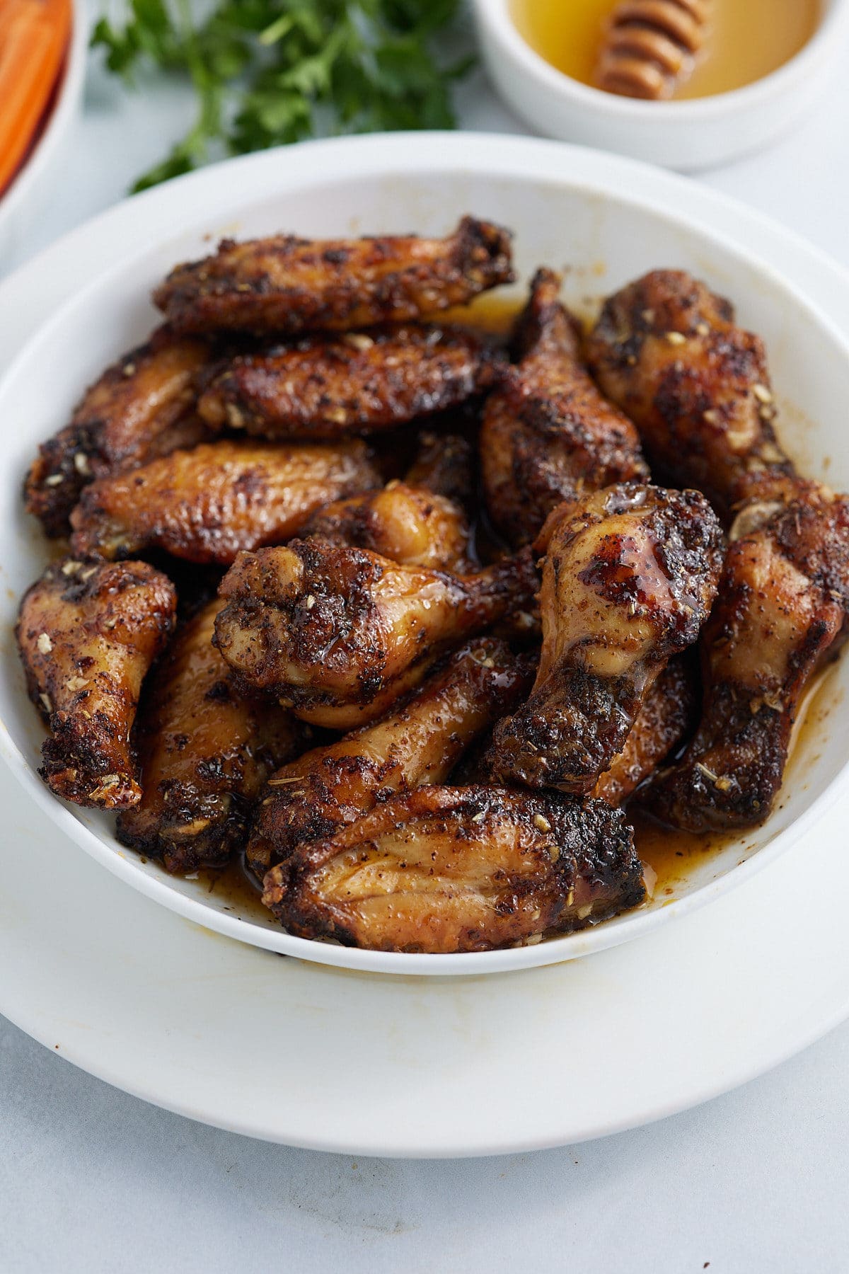 Cooked honey garlic chicken wings served in a white bowl.